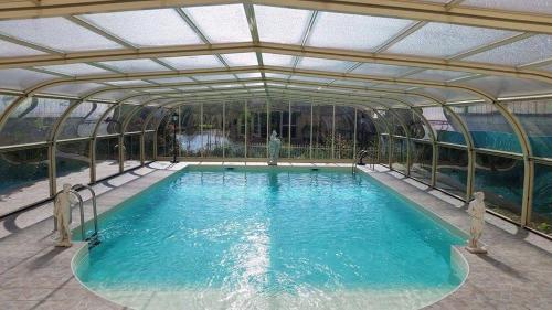 een groot zwembad met een glazen dak bij Le Clos des Cèdres b&b in La Rochefoucauld