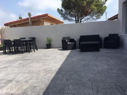 un patio avec des chaises et des tables noires et un mur dans l'établissement LA MARINA, à Galizano