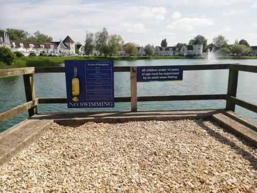 a no swimming sign on a fence next to a body of water at Lovely Lakeside lodge for families and friends in South Cerney