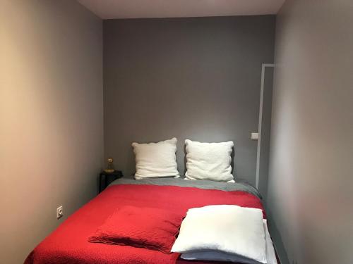 une chambre avec un lit rouge avec deux oreillers dans l'établissement Au poids du Roy, à Noyers-sur-Serein