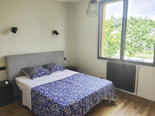 una camera da letto con un letto con un piumone blu e una finestra di Sara ad Aulnay-sous-Bois