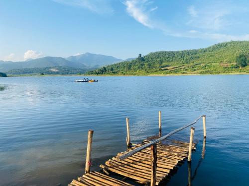 a dock on a lake with a boat in the water at Sapthapadi Villas in Lammasingi