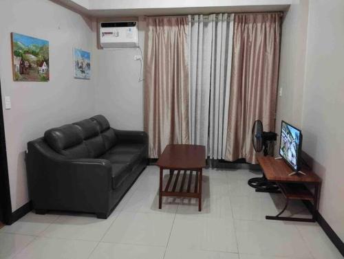 a living room with a black leather couch and a table at Spacious 1 bedroom unit in Araneta Center Cubao in Manila
