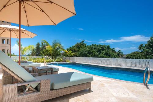 a swimming pool with chairs and an umbrella next to a pool at The Crane Resort in Saint Philip