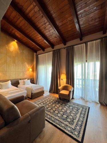 a bedroom with two beds and a couch and a room with windows at Kodra e Kuajve in Durrës