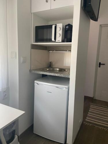 a small kitchen with a refrigerator and a microwave at RM newhost 2015 / CasaDoChico in Portalegre