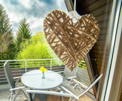 a table and chairs on a balcony with two heart decorations at Ferienhaus Rhön-Auszeit in Bischofsheim an der Rhön
