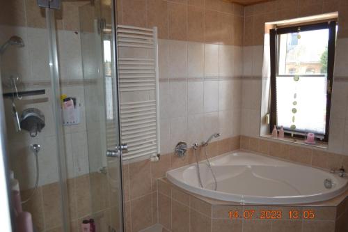een badkamer met een bad en een douche met een raam bij Ferienwohnung mit Ausblick in Wimmelburg in Wimmelburg