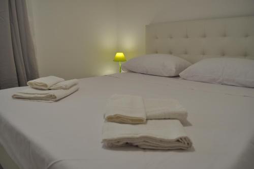 Una cama con sábanas y almohadas blancas y toallas. en LECCE AL MARE, en San Cataldo