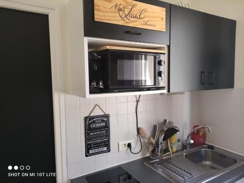 - une cuisine avec un four micro-ondes au-dessus d'un évier dans l'établissement Appartement près de la mer, à Sète