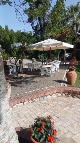a patio with tables and an umbrella and flowers at FONDAZIONE VILLA POINT ONLUS in San Felice Circeo