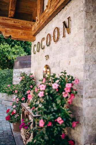 a building with pink roses and a sign that reads cooomed at Wellnessresidenz Alpenrose in Maurach