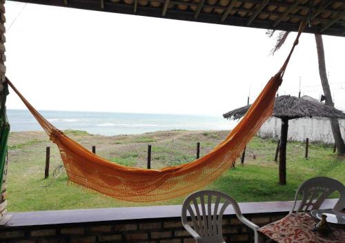 a hammock in a room with a view of the ocean at Condominio Praia Caraubas in Caraúbas