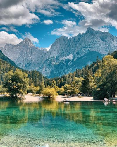 a lake with trees and mountains in the background at Cosy Forest in Kranjska Gora