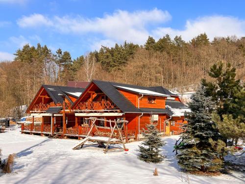 a large wooden cabin in the snow with trees at Hospůdka pod Rablinů in Kašava