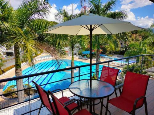 a table with chairs and an umbrella next to a swimming pool at APARTASOLES SANTAFE in Santa Fe de Antioquia