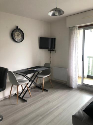 - un salon avec une table, des chaises et une horloge dans l'établissement Jardin de la plage, à Villers-sur-Mer