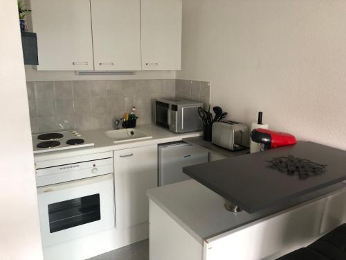 une petite cuisine avec des armoires blanches et un micro-ondes dans l'établissement Jardin de la plage, à Villers-sur-Mer