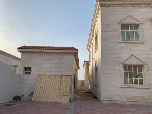 a white building with a garage next to a house at Vila XVIP in Ras al Khaimah