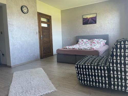 a room with a bed and a chair and a clock at Lawendowy apartament in Mszana Dolna