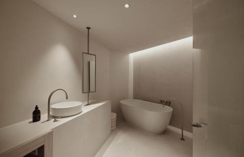 a white bathroom with a tub and a sink at Enso District Hotel in Knokke-Heist