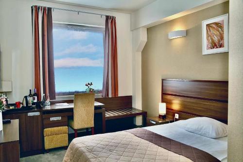 a hotel room with a bed and a desk and a window at Hotel Tęczowy Młyn in Kielce