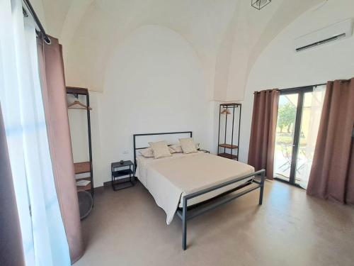 Habitación blanca con cama y ventana en Casina Pompiliano, en Nardò