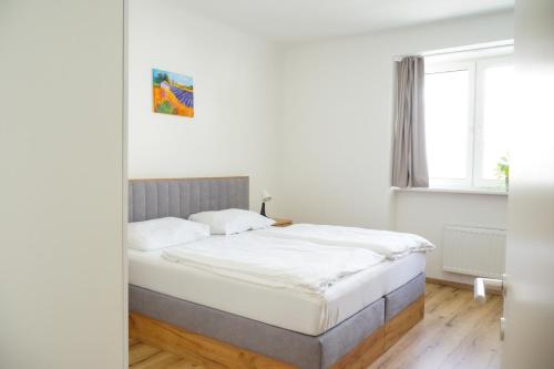 Chill & Relax Apartments Purbach في برباش ام نيوسيدله: غرفة نوم بسرير وملاءات بيضاء ونافذة