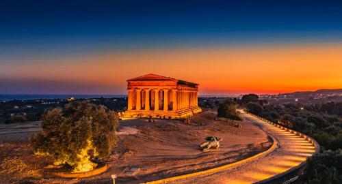 an ancient building with a sunset in the background at U Curtigliu apartment in Realmonte