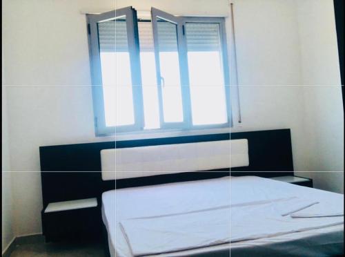 Zimmer mit einem Bett, einem Fenster und einem Spiegel in der Unterkunft H Apartment Vlorë in Vlorë