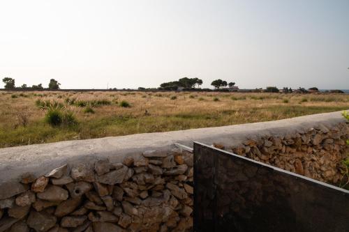 uma parede de pedra ao lado de um campo com árvores em Sweet Sicily Apartments em Carini