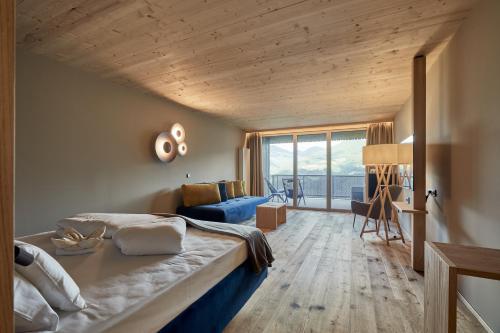 a bedroom with a large bed and a blue couch at Vinumhotel Feldthurnerhof in Feldthurns