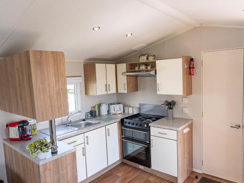 a kitchen with white cabinets and a stove top oven at Caravan Skegness 8 Berth in Skegness