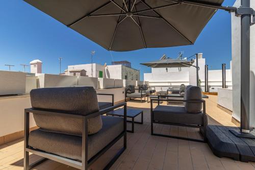 eine Terrasse mit Stühlen und einem Sonnenschirm auf dem Dach in der Unterkunft Allo Apartments San Roque 3ºC in Cádiz