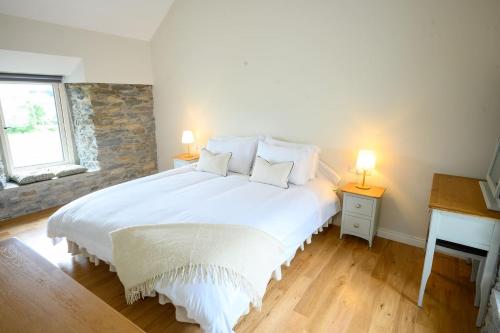 a bedroom with a large white bed with two lamps at Killarney Old School Road sleeps 6 in Killarney