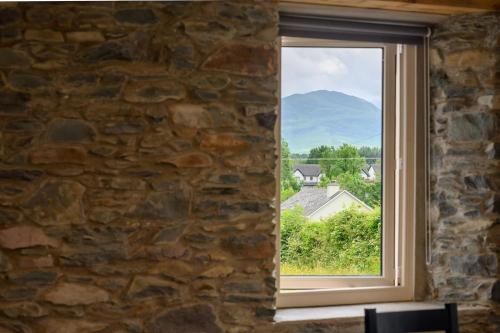 a window in a stone wall with a mountain view at Killarney Old School Road sleeps 6 in Killarney