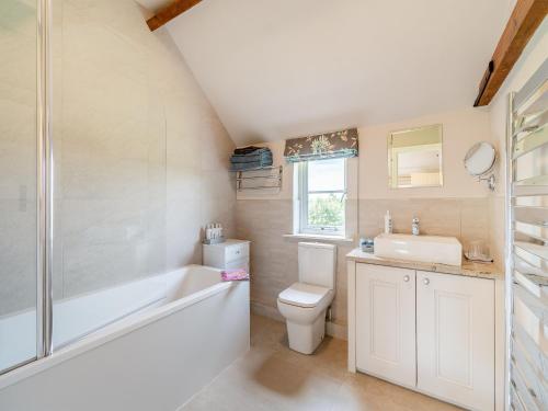 a bathroom with a tub and a toilet and a sink at Paddock Cottage in Scalford