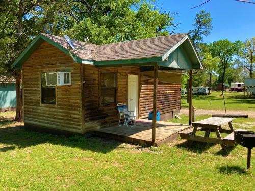 a log cabin with a picnic table and a bench at Outback Campground and Marina in Trinity