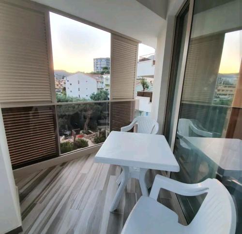 uma mesa branca e cadeiras brancas numa varanda em Sirius apartaments em Rafailovici
