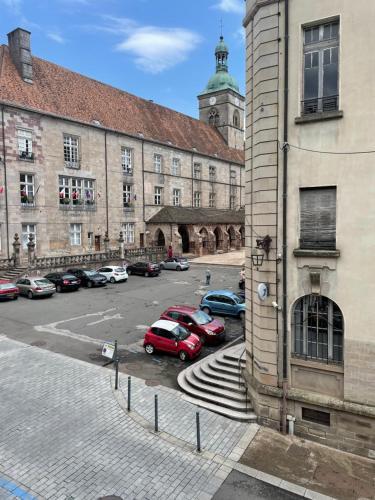 un gran edificio con coches estacionados en un estacionamiento en F1 Centre Historique Saint Valbert, en Luxeuil-les-Bains
