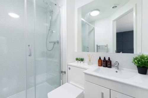 a white bathroom with a shower and a sink at Modern Four Bedroom Four Bathroom Home in Cheltenham