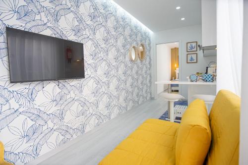 een woonkamer met een gele bank en een tv aan de muur bij Villa Beach in Nazaré