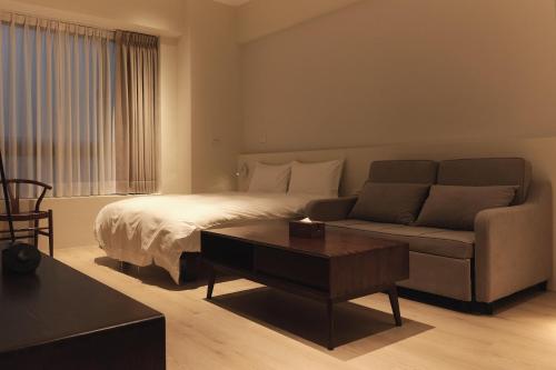 - une chambre avec un lit, un canapé et une table dans l'établissement Yueshe House, à Jiaoxi