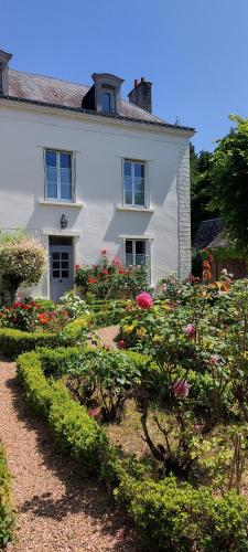 Biały dom z ogrodem przed nim w obiekcie Le Clos des Roses w mieście Parçay-les-Pins