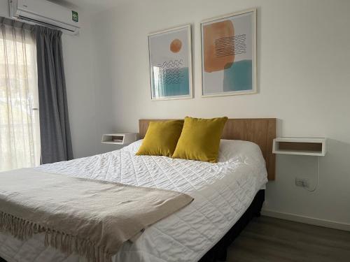 1 dormitorio con 1 cama con 2 almohadas amarillas en Departamento Villa Mercedes San Luis FUCO en Villa Mercedes