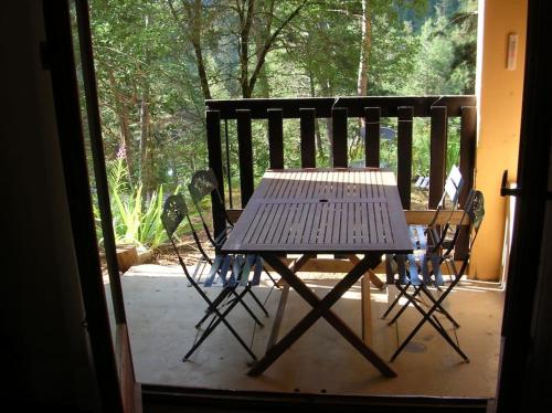une table et des chaises en bois assises sur une terrasse couverte dans l'établissement T3 au calme rez de jardin station LA COLMIANE, à Valdeblore