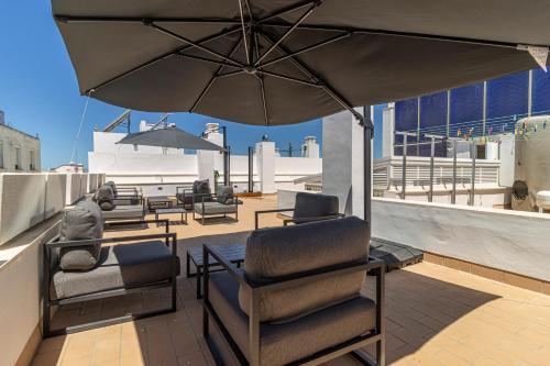 een patio met stoelen en een parasol op een dak bij Allo Apartments San Roque 1ºA in Cádiz