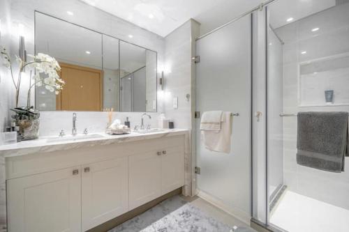 a white bathroom with a shower and a sink at Spectacular Views of Burj & Fountain - 2 BR in Dubai