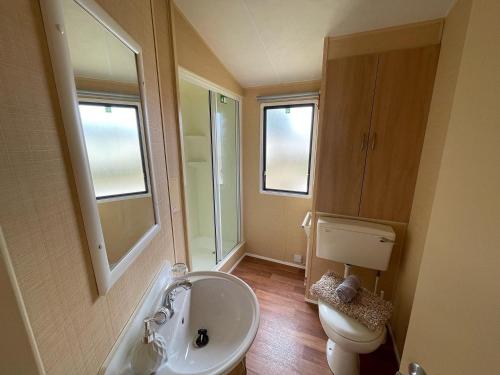 a bathroom with a sink and a toilet and a mirror at Peaceful holiday home on a park on the Kent Coast in St Margarets at Cliff