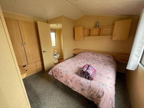 a small bedroom with a pink bed with a purse on it at Peaceful holiday home on a park on the Kent Coast in St Margarets at Cliff